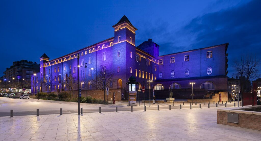 Photographie architecturale de l'ancien collège de Montauban mis en valeur par un éclairage bleu et pourpre