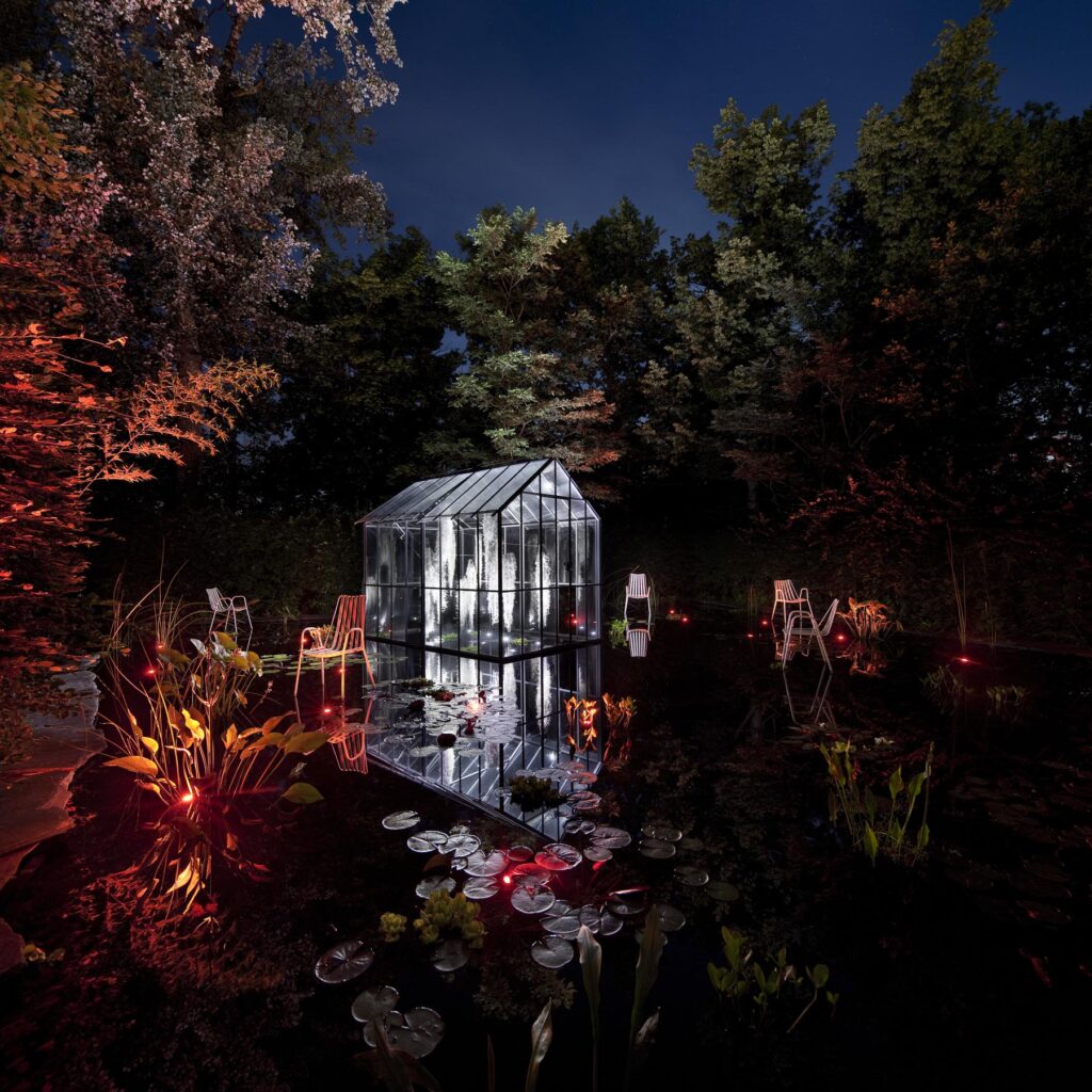 Illuminations nocturnes d'un jardin au Festival des Jardins de Chaumont: une serre semble flotter sur l'eau