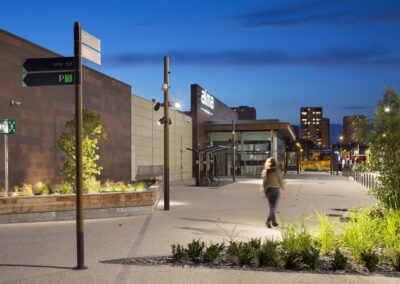 Parking de supermarché à Rennes éclairé par des mâts en bois Aubrilam, ambiance nocturne avec éclairage uniforme et moderne.